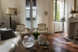 Salon frais en été avec volets mi-clos, ventilateur sur pied et bol d'eau froide sur la table basse