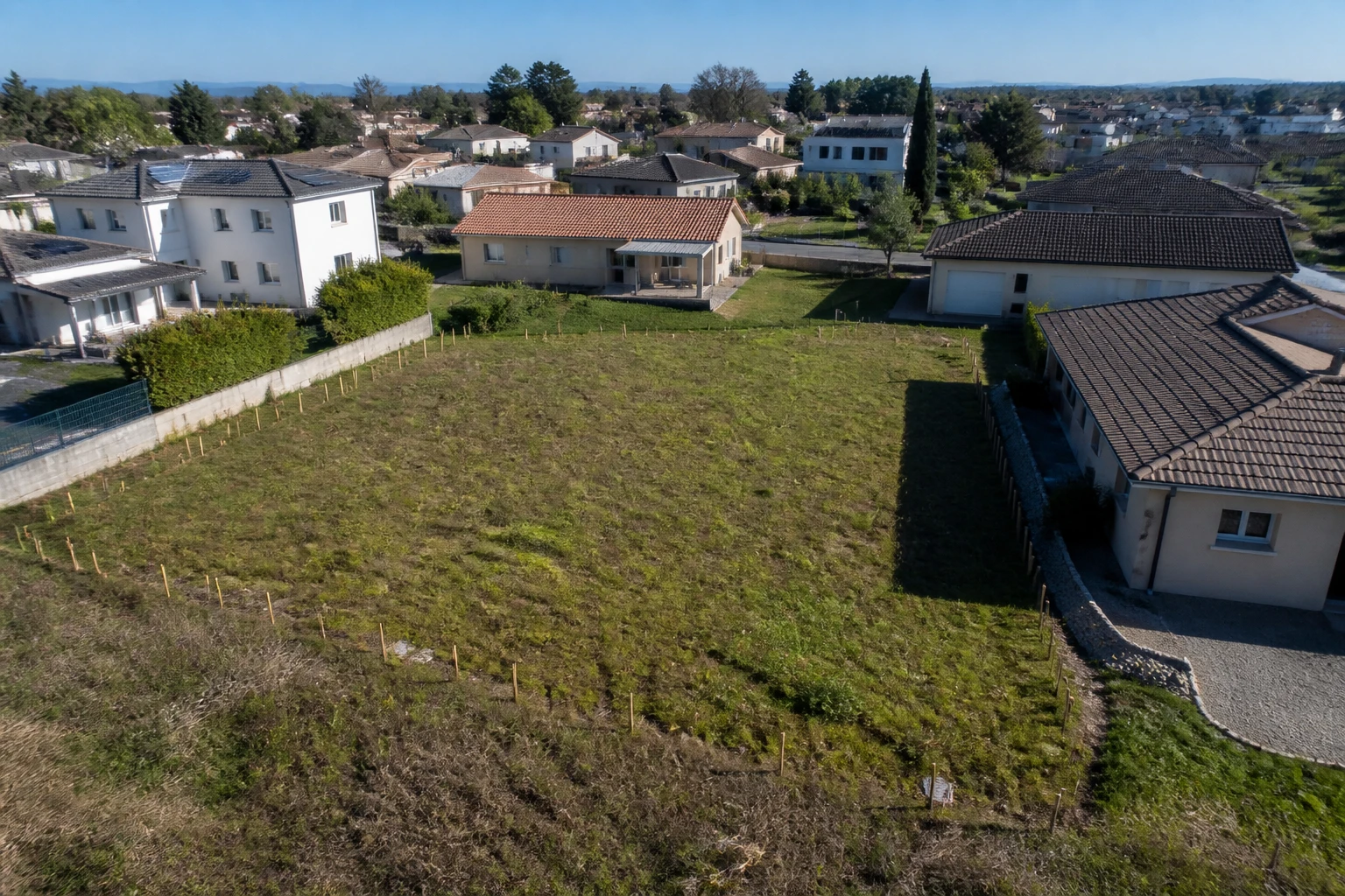 Terrain à bâtir borné en zone pavillonnaire avec piquets de délimitation plantés au sol